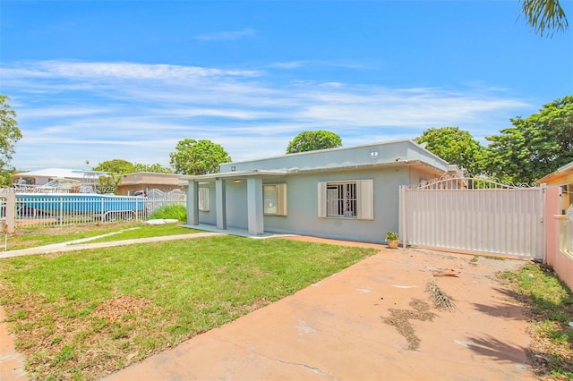 back of property with a gate, fence, a lawn, and stucco siding