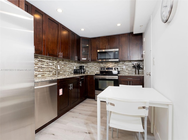 kitchen featuring dark brown cabinetry, stainless steel appliances, tasteful backsplash, light wood-type flooring, and sink