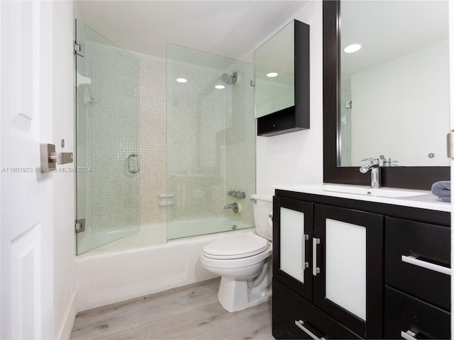 full bathroom featuring enclosed tub / shower combo, wood-type flooring, vanity, and toilet