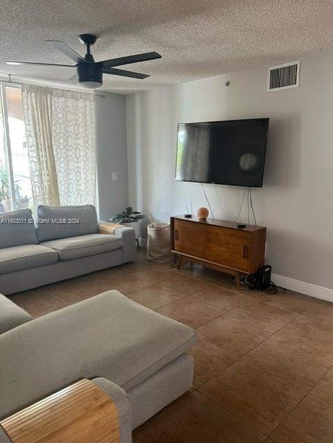 living room with ceiling fan and a textured ceiling