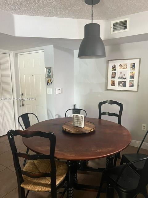 tiled dining room featuring a textured ceiling