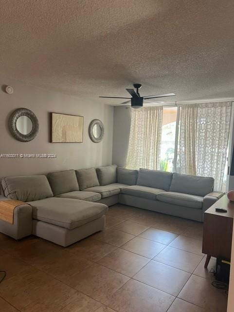 living room featuring ceiling fan, light tile patterned floors, and a textured ceiling