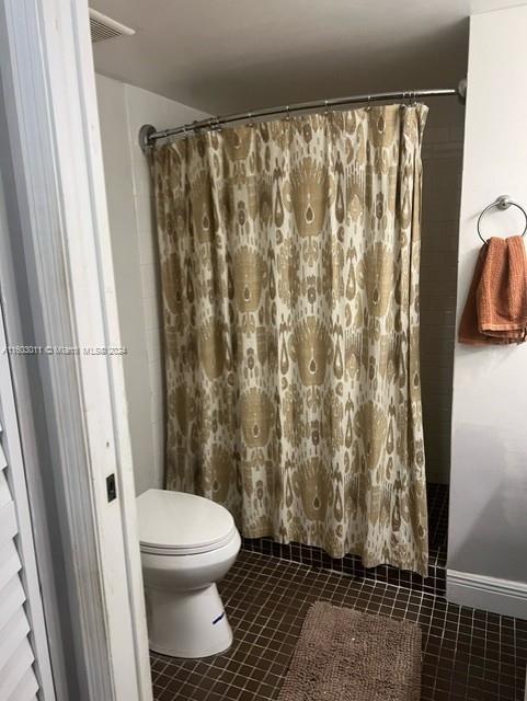 bathroom featuring toilet, tile patterned flooring, and walk in shower