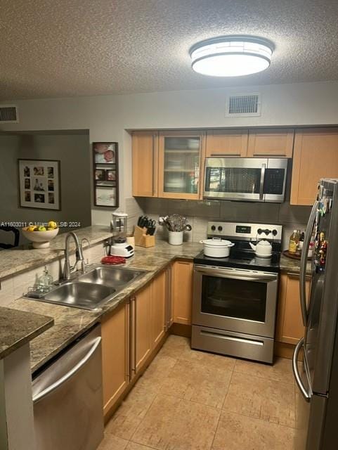 kitchen with sink, a textured ceiling, stone countertops, kitchen peninsula, and stainless steel appliances