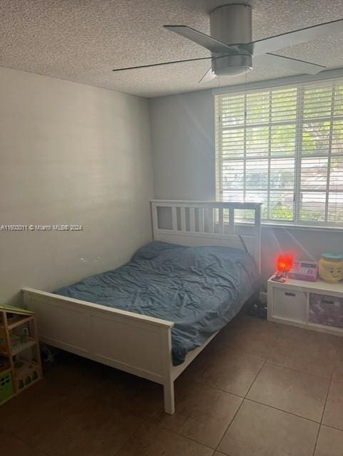 tiled bedroom featuring ceiling fan and a textured ceiling