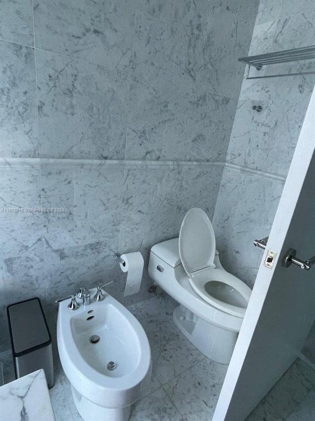 bathroom with a bidet, tile flooring, tile walls, and toilet