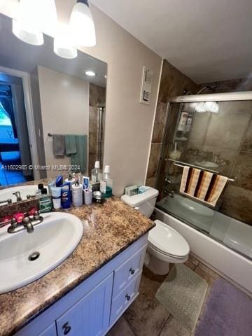 full bathroom featuring tile patterned flooring, vanity, bath / shower combo with glass door, and toilet