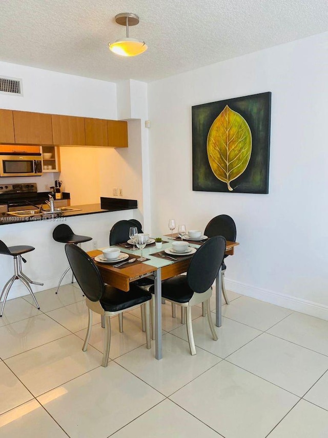 dining space featuring light tile flooring and a textured ceiling