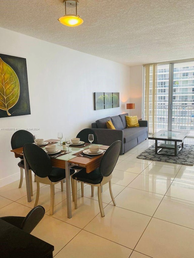 tiled dining room with a textured ceiling and floor to ceiling windows