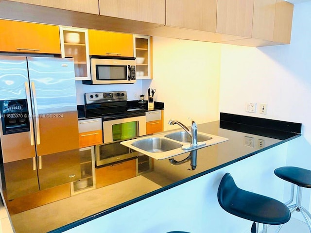kitchen with glass insert cabinets, a sink, dark countertops, a peninsula, and stainless steel appliances