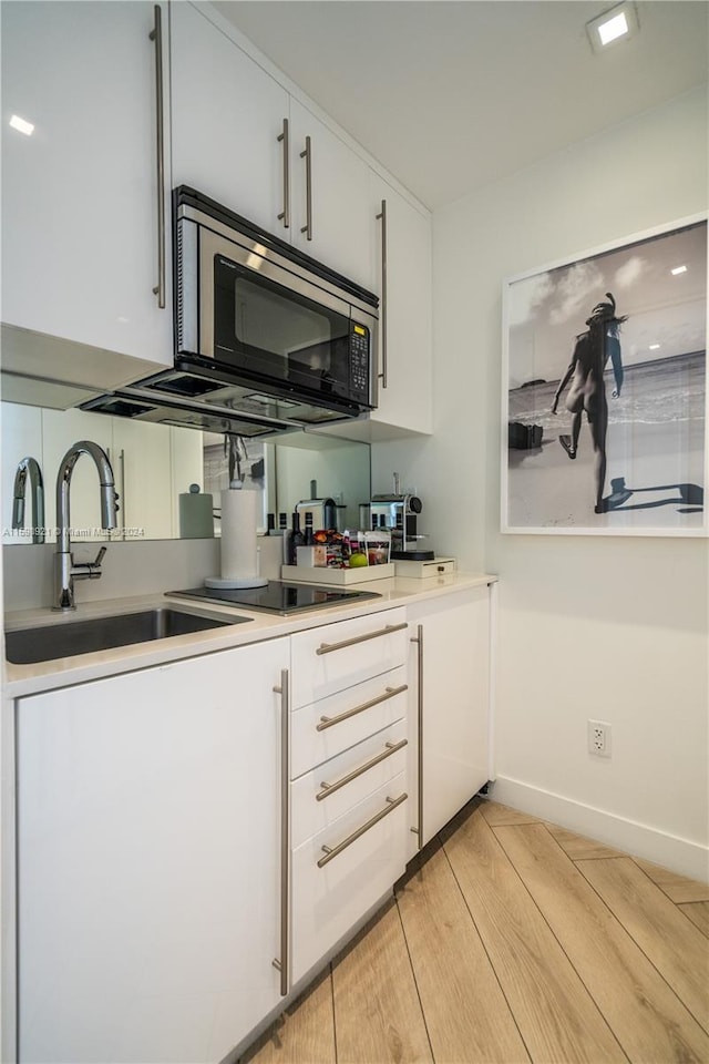 kitchen with sink, white cabinets, and light wood-type flooring