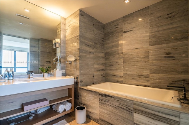 bathroom with vanity, tile walls, and tiled bath