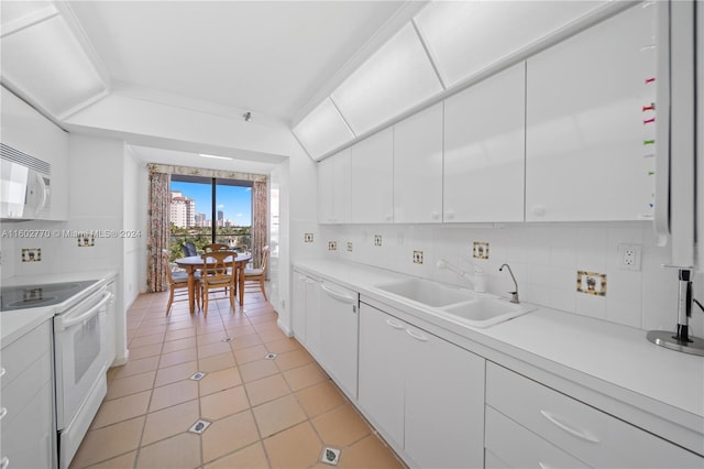 kitchen with decorative backsplash, sink, white cabinets, and white appliances