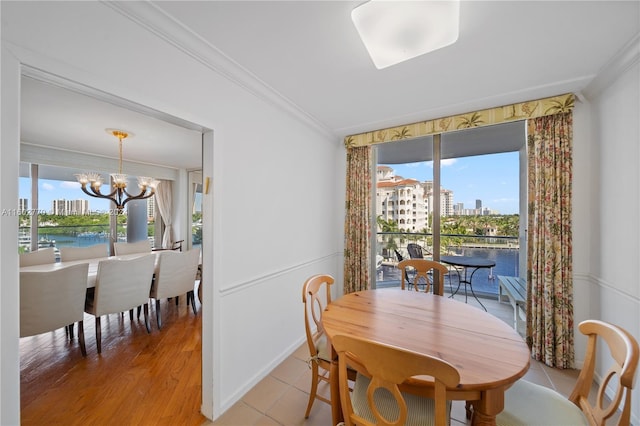 tiled dining room featuring crown molding, a water view, and a chandelier