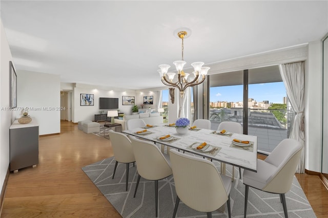 dining area with light hardwood / wood-style floors and an inviting chandelier