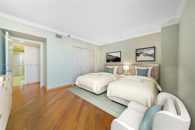 bedroom featuring light hardwood / wood-style floors, crown molding, and a closet