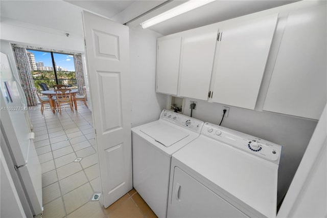 laundry area featuring washing machine and clothes dryer, cabinets, and light tile patterned flooring