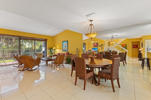 dining space featuring a textured ceiling, light tile patterned floors, and vaulted ceiling