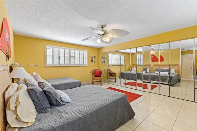 tiled bedroom with ceiling fan, multiple windows, and a textured ceiling