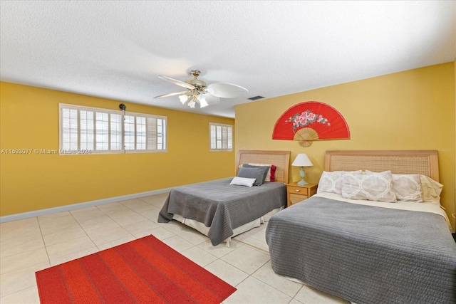 bedroom with ceiling fan, multiple windows, a textured ceiling, and light tile patterned flooring