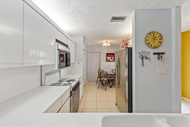 kitchen featuring white cabinetry, light tile patterned floors, stainless steel appliances, and a textured ceiling