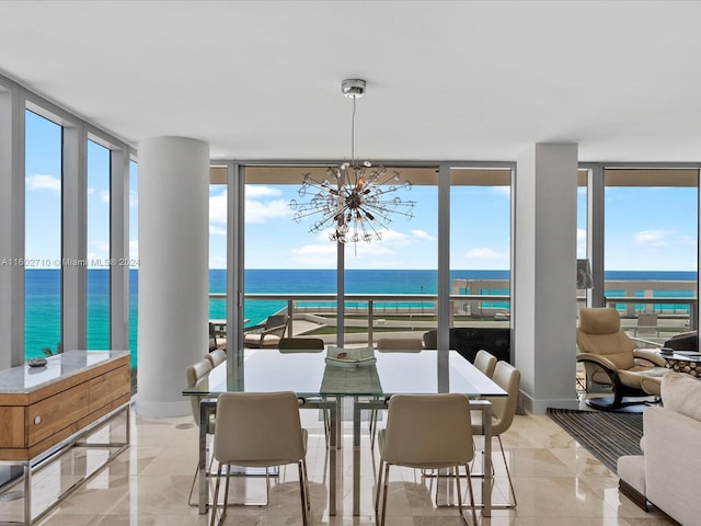 dining room featuring a water view, a wall of windows, a wealth of natural light, and an inviting chandelier