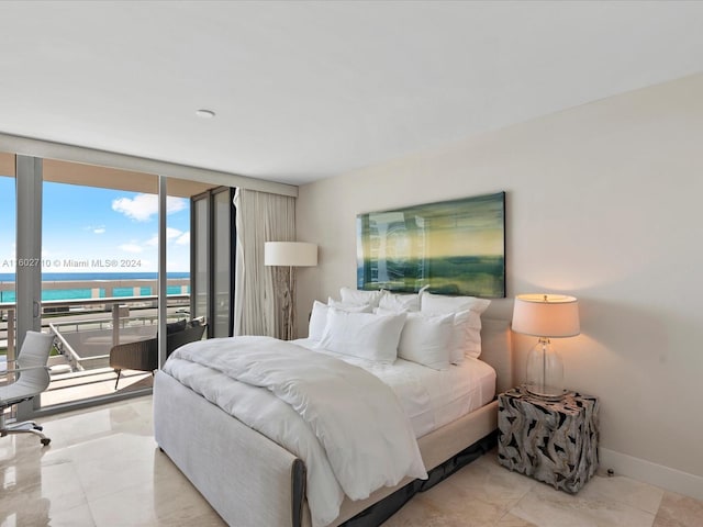 bedroom with expansive windows, a water view, and access to outside