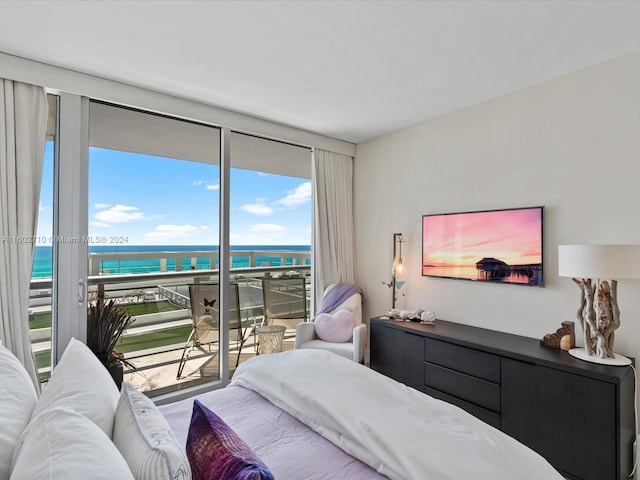 bedroom featuring floor to ceiling windows, a water view, and access to outside