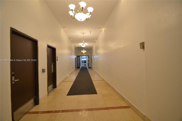 corridor with light tile patterned floors and a notable chandelier