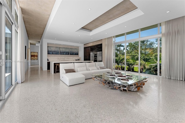 living room with a raised ceiling and floor to ceiling windows