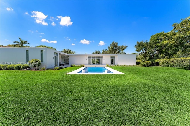 rear view of property with a fenced in pool and a lawn