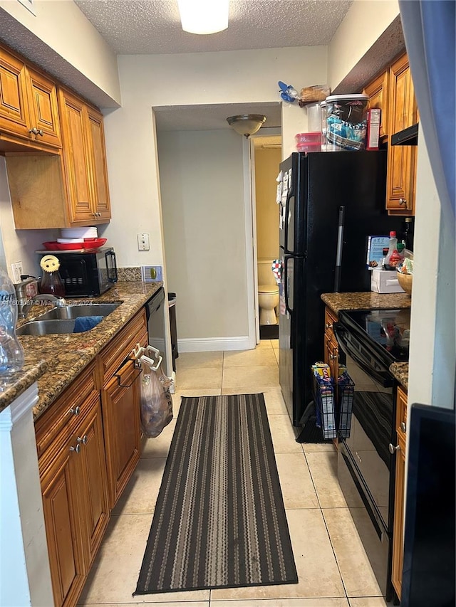 kitchen with sink, black appliances, a textured ceiling, and light tile floors