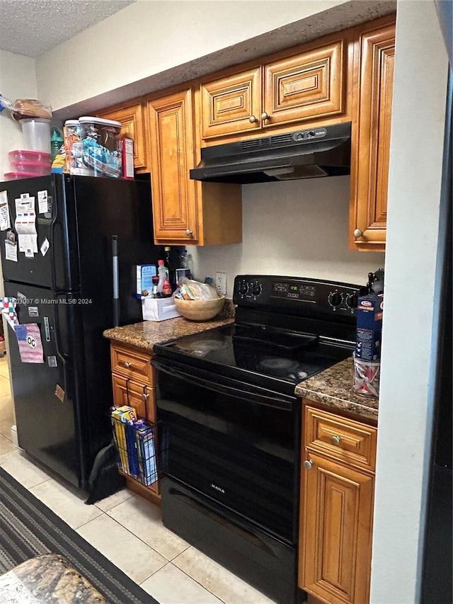 kitchen with a textured ceiling, dark stone countertops, black appliances, and light tile patterned flooring