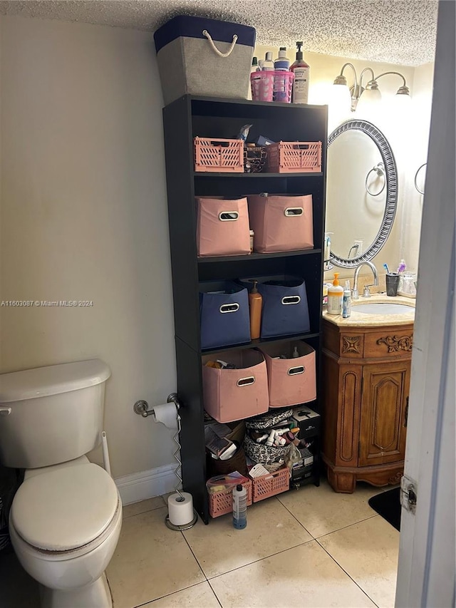 bathroom with a textured ceiling, toilet, vanity, and tile patterned flooring