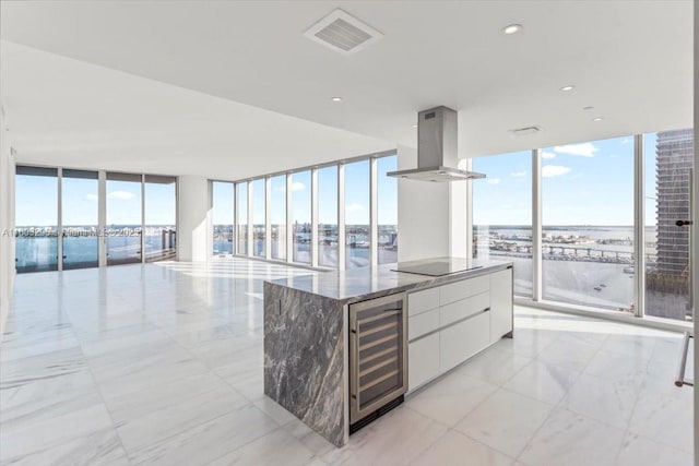 kitchen with a wall of windows, wine cooler, visible vents, and island range hood