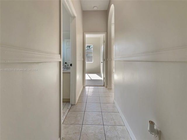 corridor featuring sink and light tile floors