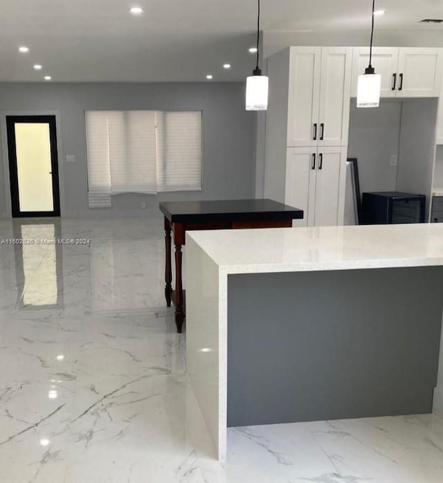 kitchen with white cabinets, decorative light fixtures, and light tile floors