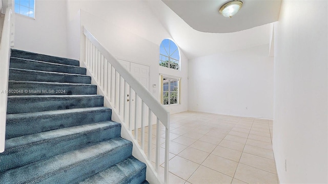 stairs featuring tile patterned flooring and vaulted ceiling