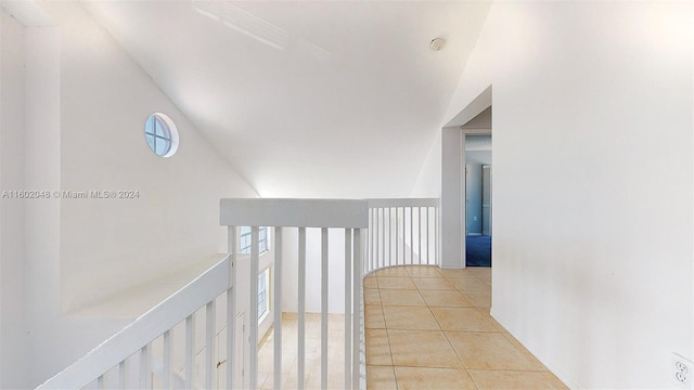 corridor with light tile patterned flooring, lofted ceiling, and a healthy amount of sunlight