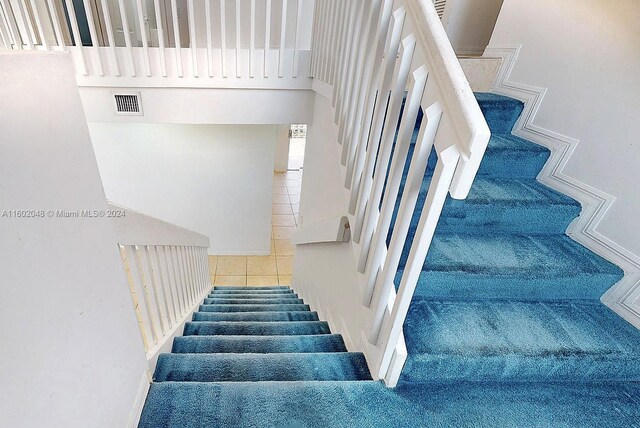 stairs with tile patterned floors and a towering ceiling