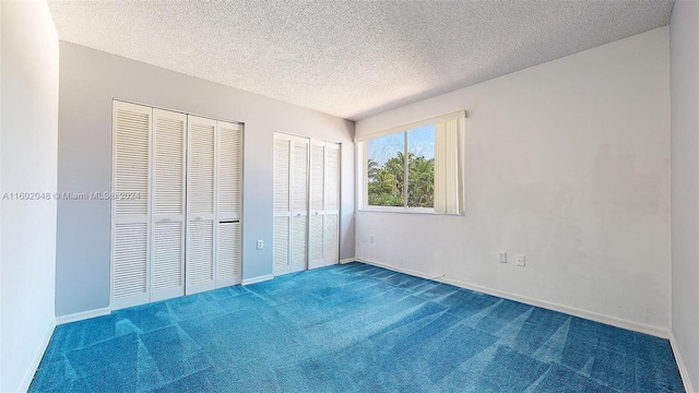 unfurnished bedroom featuring multiple closets, carpet floors, and a textured ceiling