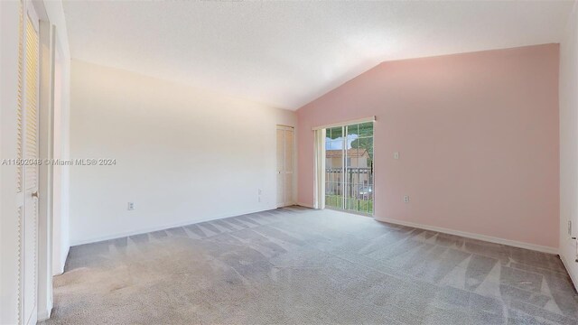 spare room with carpet and vaulted ceiling