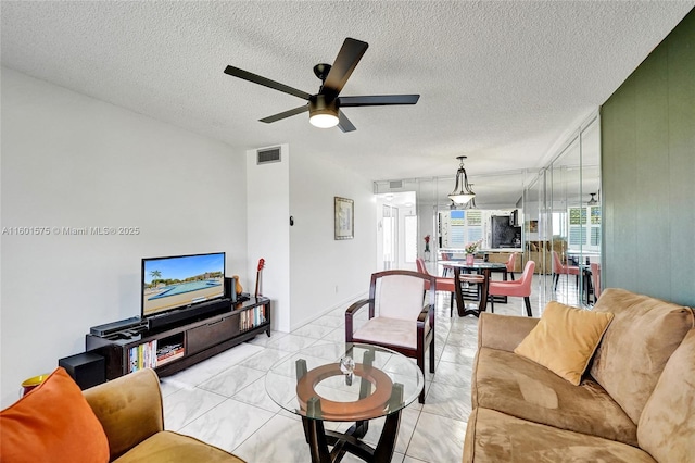 living room with ceiling fan and a textured ceiling