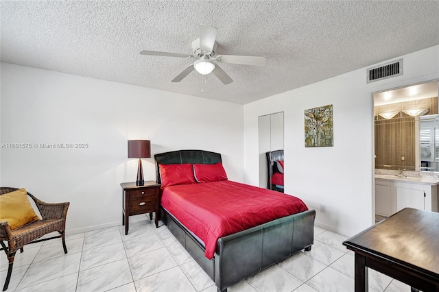 bedroom featuring sink, ensuite bath, ceiling fan, a textured ceiling, and a closet