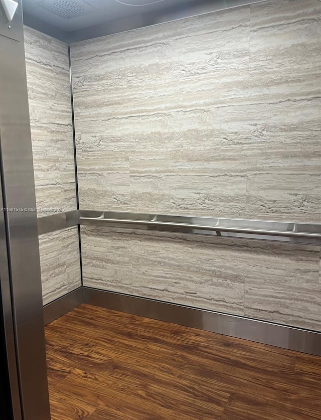 details with elevator and hardwood / wood-style flooring