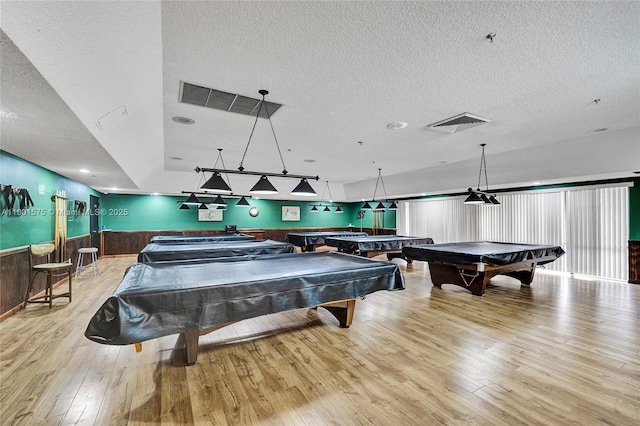 game room with a textured ceiling, light wood-type flooring, and pool table