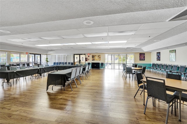 dining space featuring hardwood / wood-style flooring, plenty of natural light, and a drop ceiling