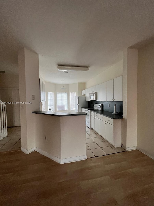 kitchen featuring white cabinets, appliances with stainless steel finishes, light tile floors, and kitchen peninsula