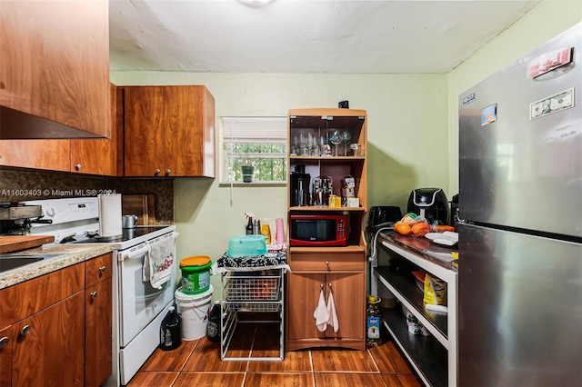 kitchen featuring stainless steel fridge, black microwave, custom range hood, dark tile flooring, and white range with electric cooktop