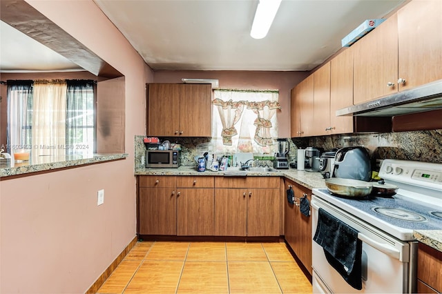 kitchen with white range with electric cooktop, light stone countertops, sink, tasteful backsplash, and light tile floors